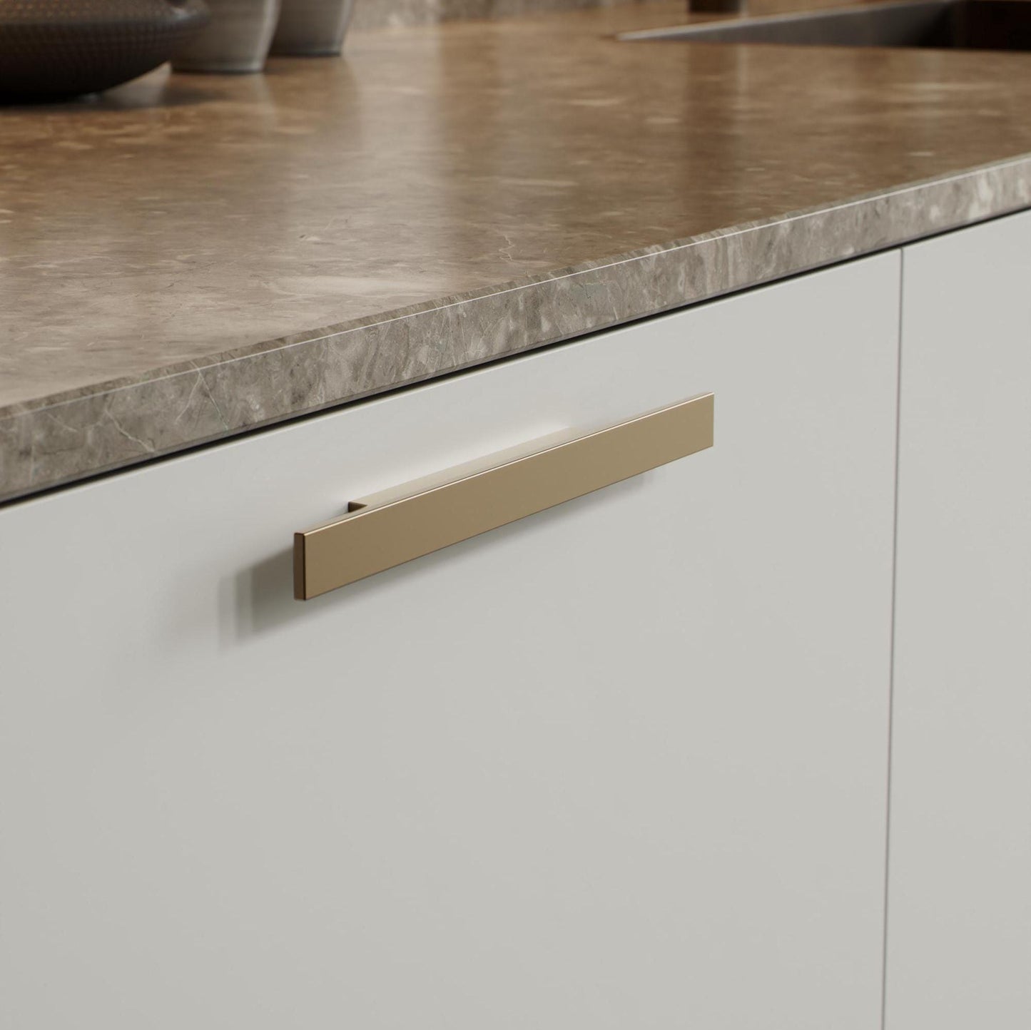 May include: A white cabinet door with a gold metal handle. The handle is rectangular and has a slightly curved edge.